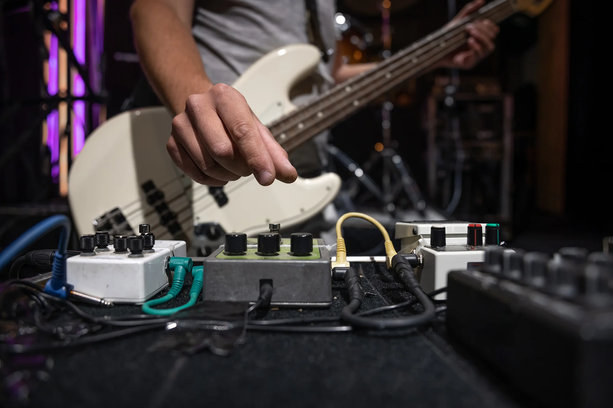 bass-guitar-player-on-stage-with-set-of-distortion-effect-pedals.webp