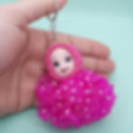 Close-up of a pink polka-dot tulle doll keychain held by a hand
