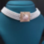 Close-up of a 4-row white pearl necklace with a rose gold floral centerpiece and matching earrings, high-quality