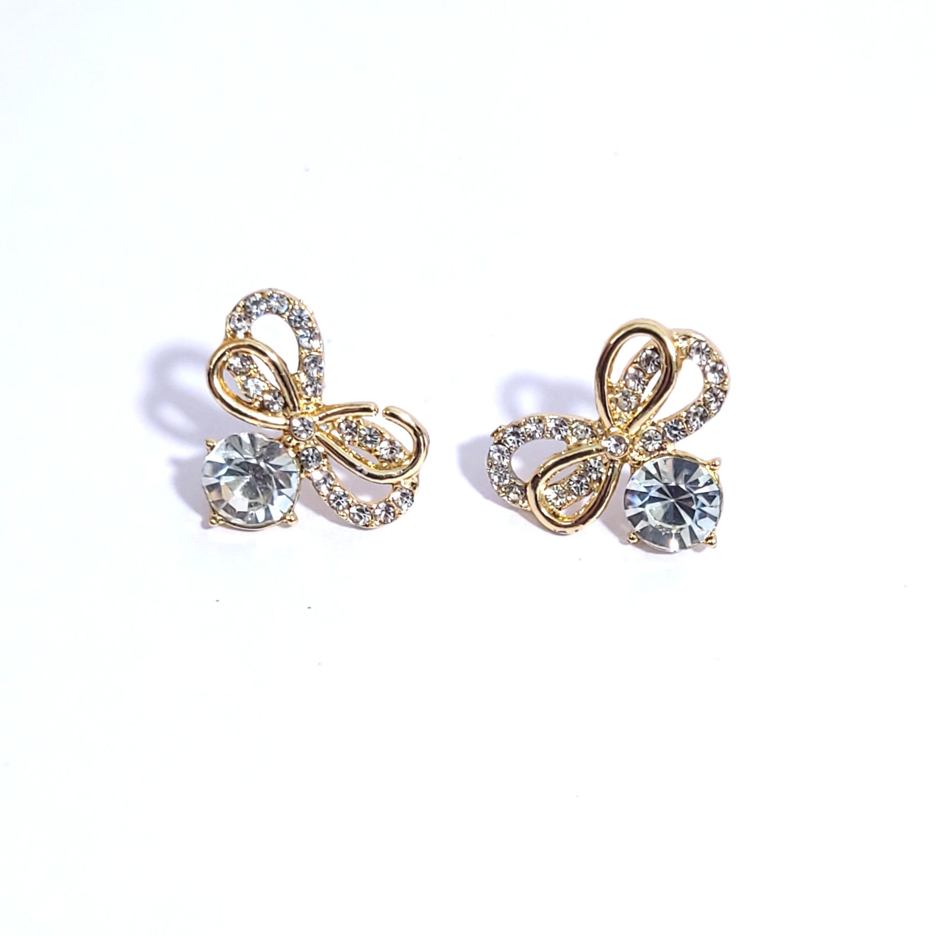 Pair of gold-plated bow-knot stud earrings encrusted with small pavé crystals and a large central round gemstone.