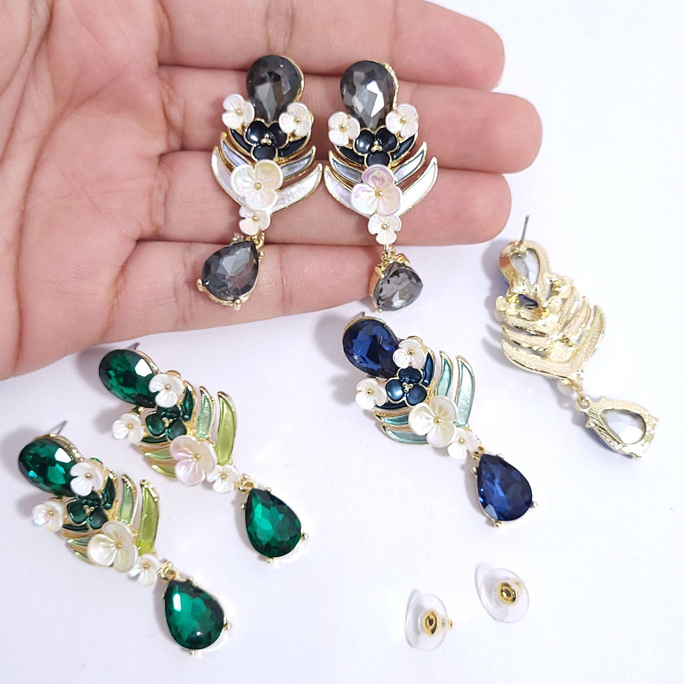 Thumbnail: A pair of ornate gold-finished drop earrings featuring white and black enamel flowers, small crystal accents, and a large fac