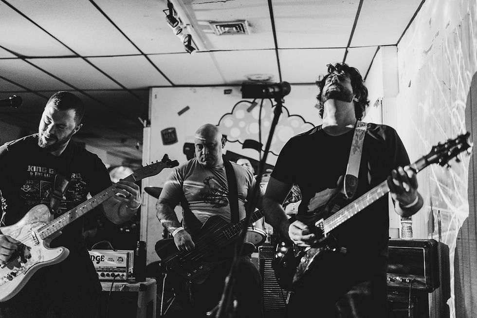 A band playing on small stage in black and white.