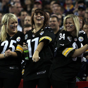 Smiling women wearing Pittsburgh Steelers jerseys in bleachers at game