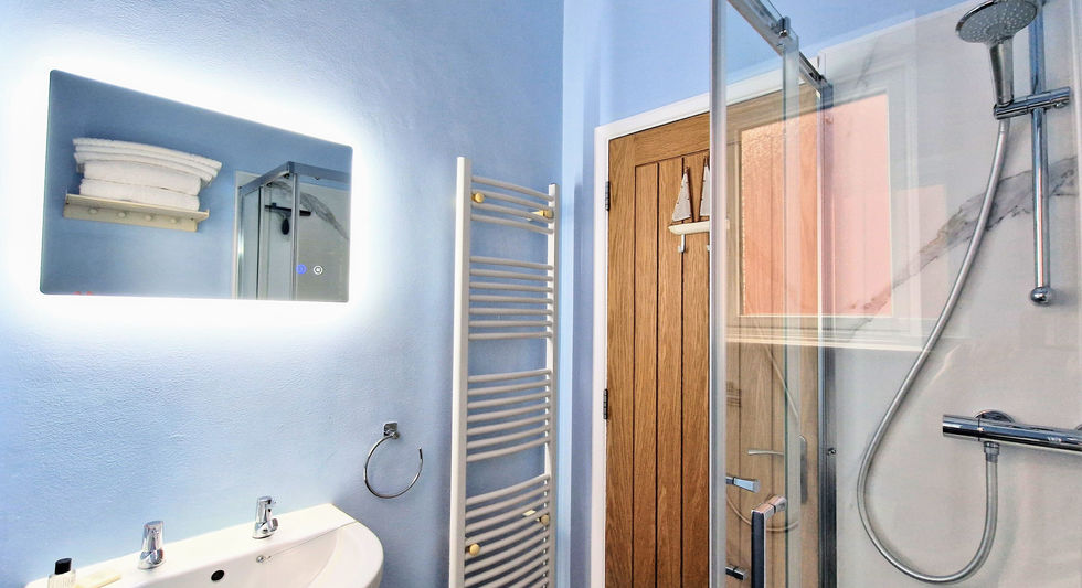 Contemporary blue bathroom in Apartment 3 at Beachside Eastbourne with a walk-in shower and large mirror.