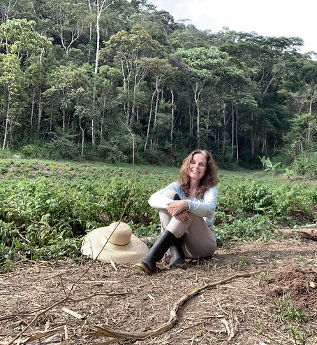 Eliana sentada em frente ao campo de cultivos de Valeriana