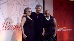 three women smiling and posing on stage