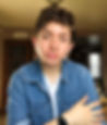 A person with short brown hair wearing a denim shirt in front of a brown background