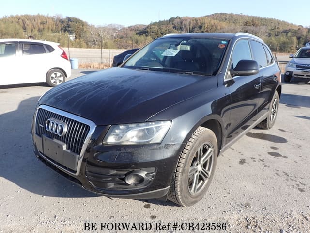 A grey sports car speeding down a highway at night.