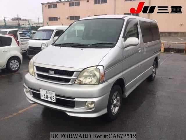 A grey JDM sports car speeding down a highway at night.