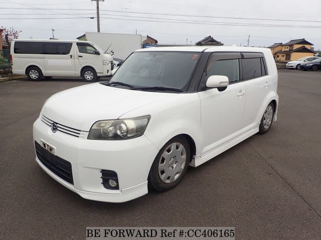 A grey sports car speeding down a highway at night.