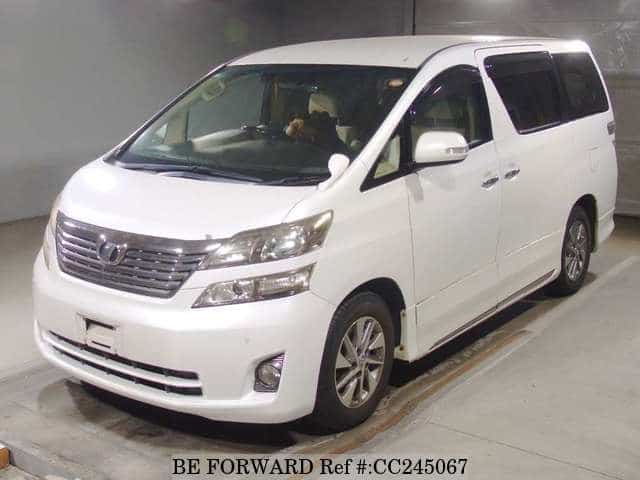 A grey sports car speeding down a highway at night.