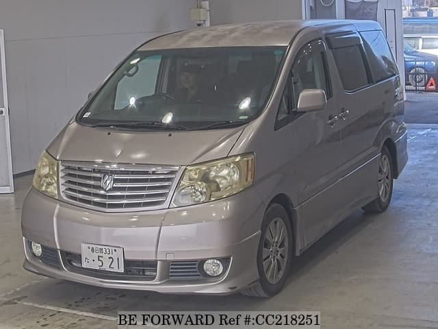 A grey sports car speeding down a highway at night.