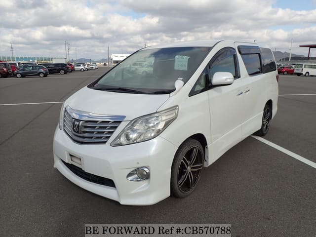 A grey sports car speeding down a highway at night.