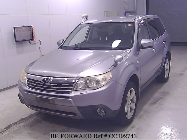 A grey sports car speeding down a highway at night.