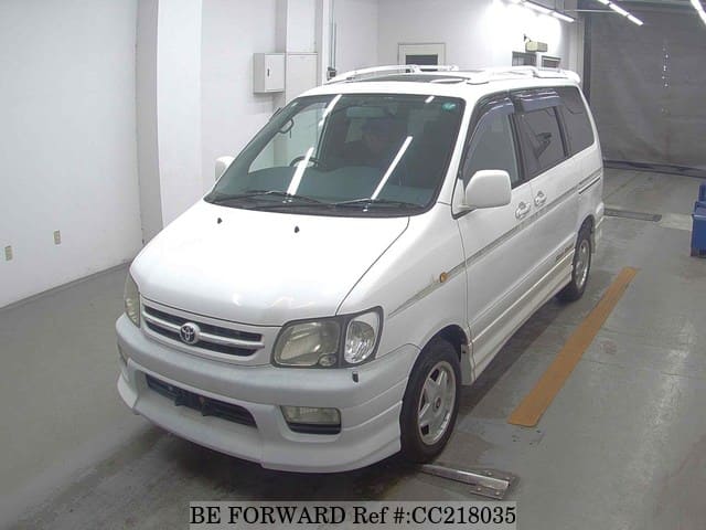 A grey sports car speeding down a highway at night.
