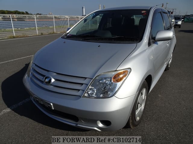 A grey sports car speeding down a highway at night.