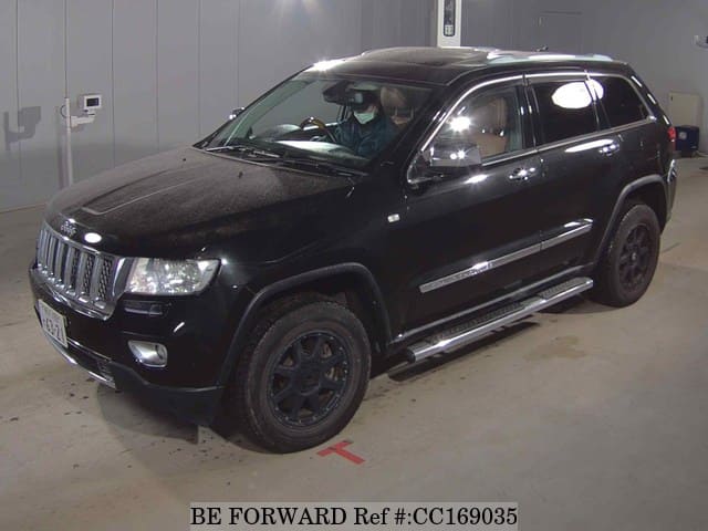 A grey sports car speeding down a highway at night.