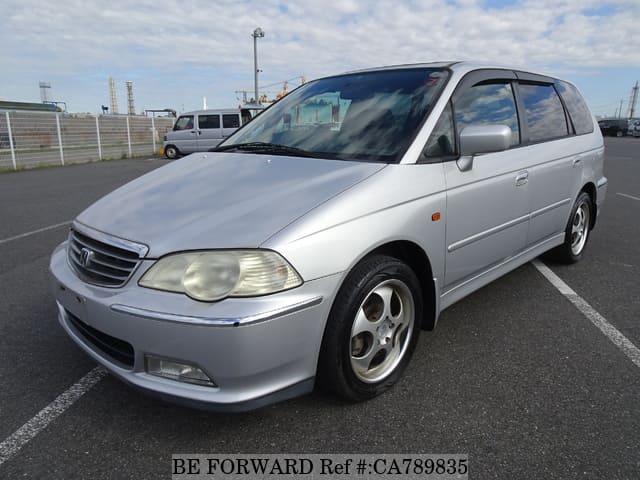 A grey JDM sports car speeding down a highway at night.