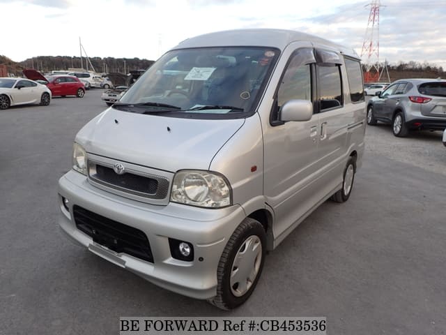 A grey JDM sports car speeding down a highway at night.