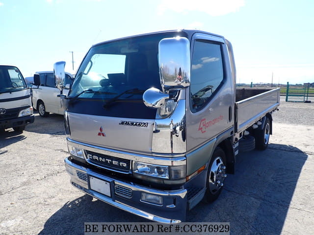 A grey sports car speeding down a highway at night.