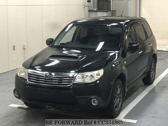 A grey sports car speeding down a highway at night.