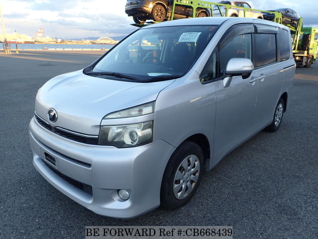 A grey sports car speeding down a highway at night.