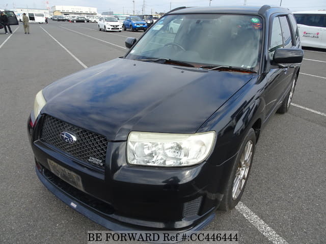 A grey sports car speeding down a highway at night.