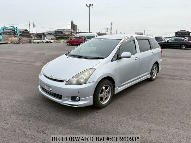 A grey sports car speeding down a highway at night.
