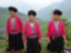 Three elderly Red Yao women from China's Long Hair Village with long, thick jet-black hair in traditional buns and vibrant pink costumes