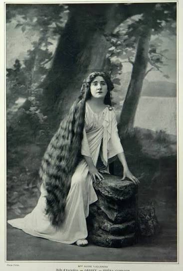 Aline Vallandri Edwardian opera singer with legendary floor-length hair, vintage 1910s portrait seated in forest by tree stump, long golden locks cascading to ground, ethereal gown and natural setting, Belle Époque beauty