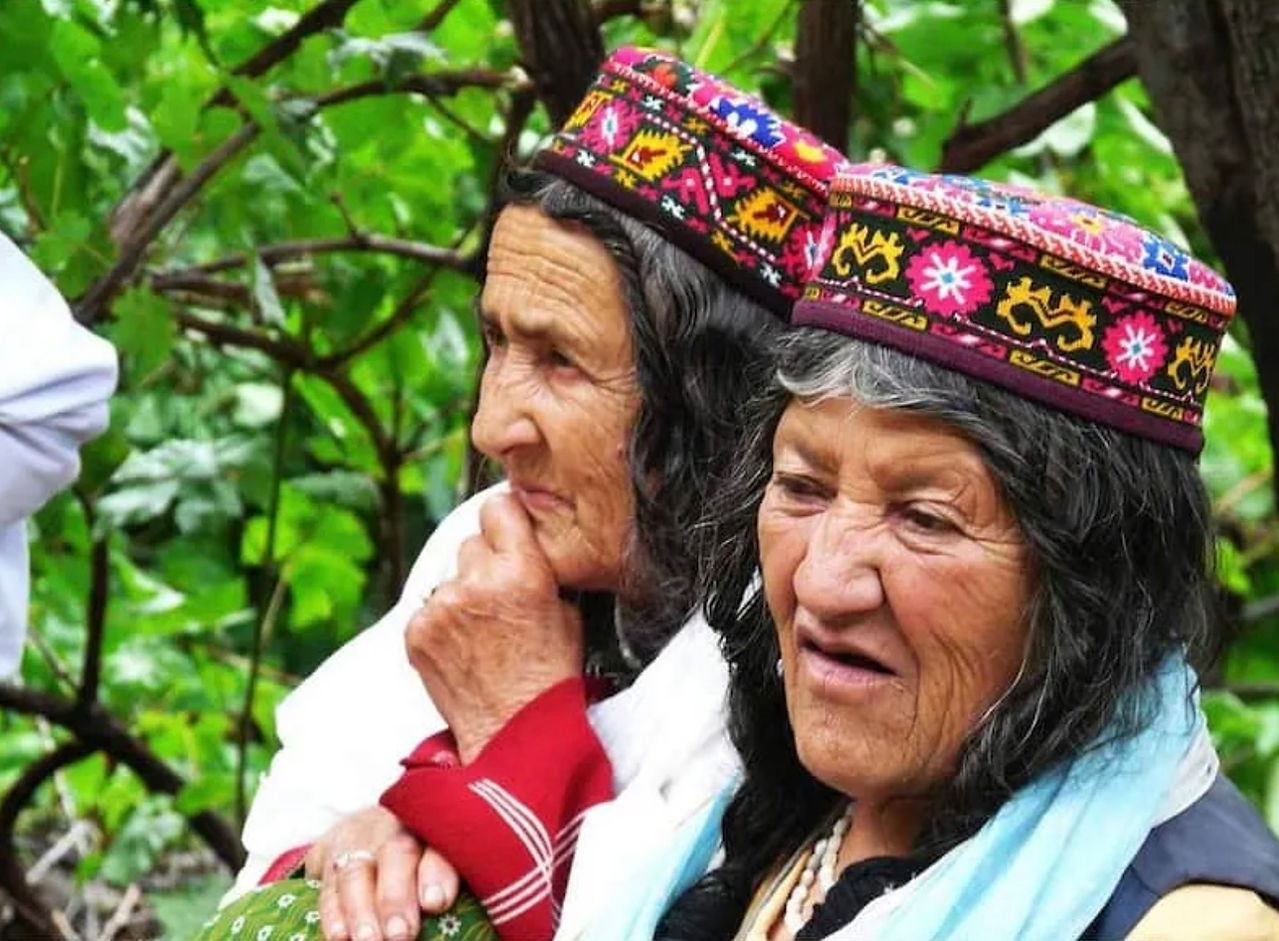 Elderly Hunza Valley women with naturally dark hair wearing traditional embroidered caps, Pakistan