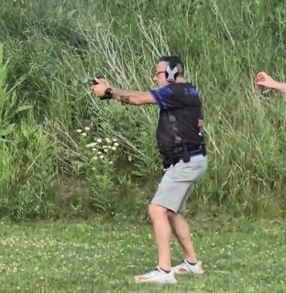 Shooter aiming a handgun during a USPSA competition.