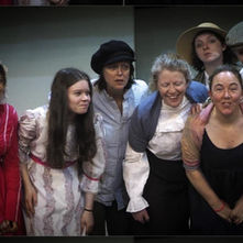 Group shot of actors in period clothing, smiling and posing together