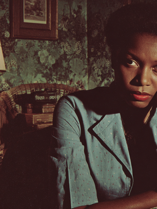 A black woman exhausted with a large Velvet spider on the lamp shade