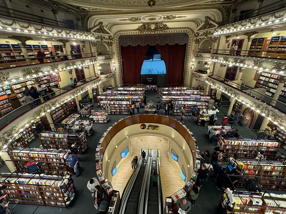 Luxurious bookstore in a former theater with ornate balconies. People browse bookshelves on multiple levels. Warm lighting adds elegance.