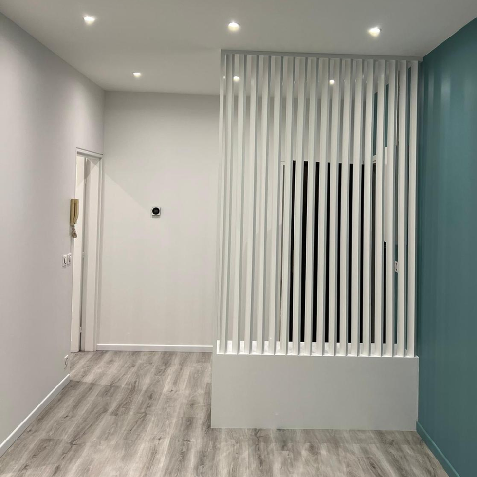 Modern interior with slatted partition and teal accent wall.