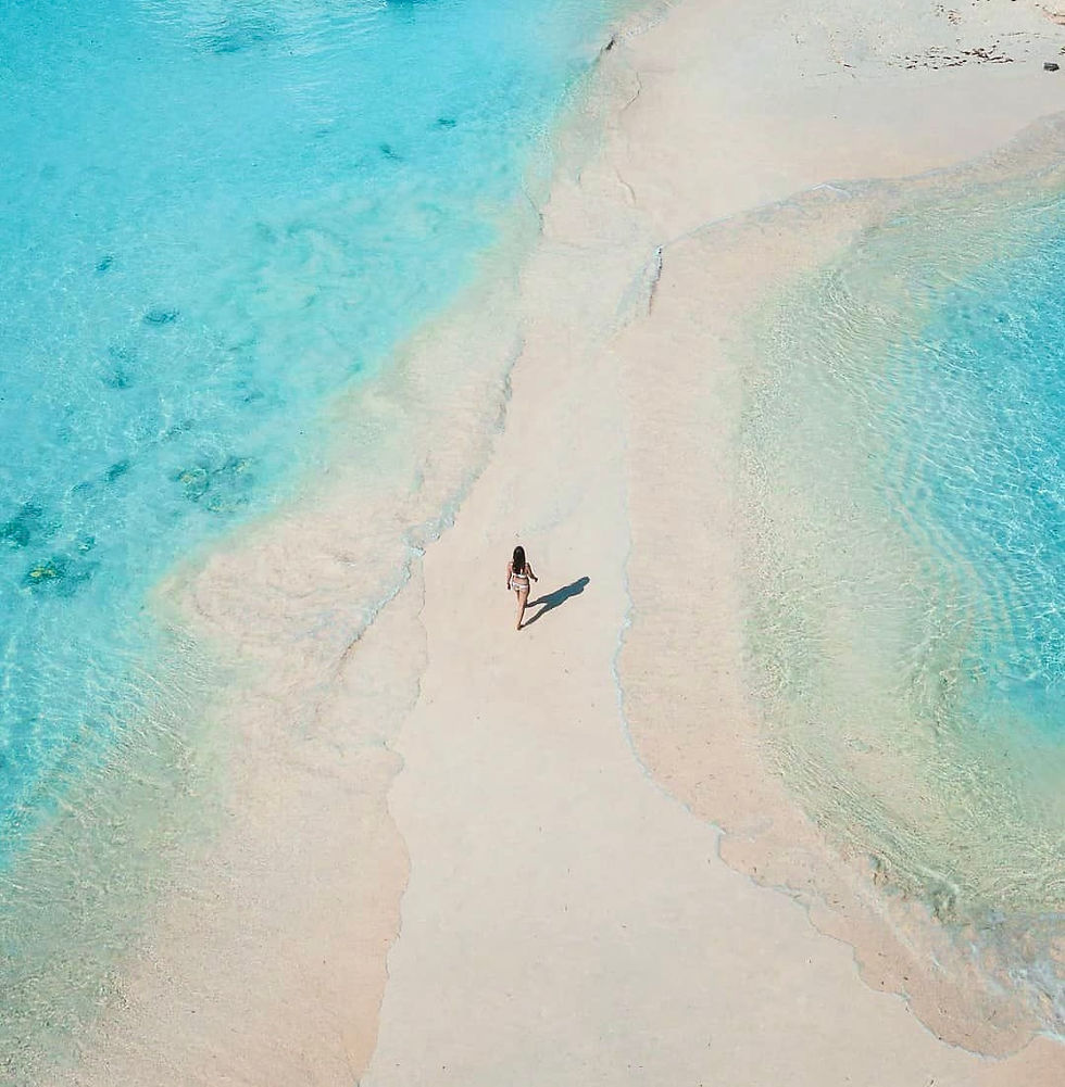 Sandbar: Aerial view of a person walking alone on a white sandbar surrounded by turquoise water in Exuma
