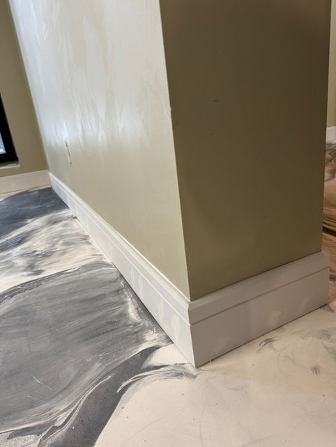 White baseboard corner detail installed beside decorative epoxy flooring in Boyle, Alberta