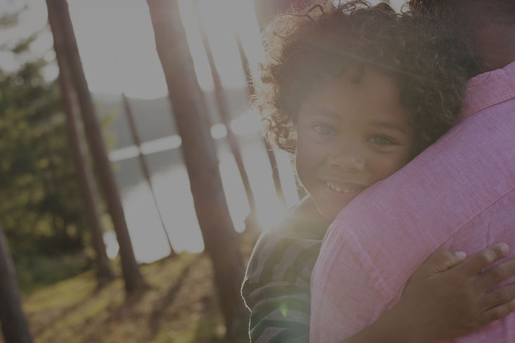 Mother holding young child smiling during virtual autism evaluation support