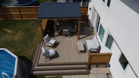 brown and tan composite deck with metal roof gazebo looking over above ground pool