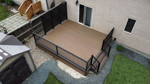 brown colored composite deck with black aluminum railing and hideaway privacy screens