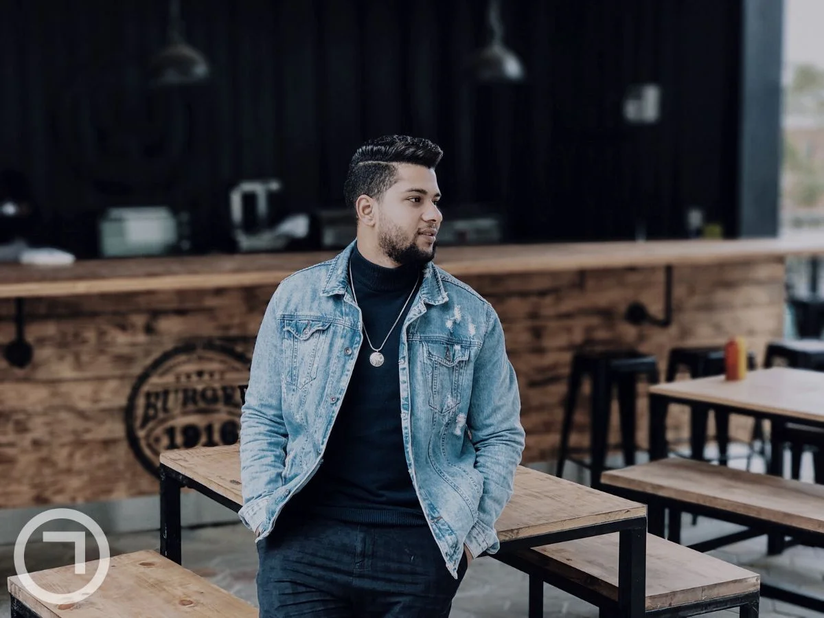 A man wearing a denim jacket in a cafe