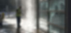 A man in a hi-vis jacket jet washing the exterior of an office building