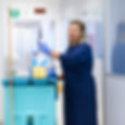 A female cleaning contractor standing an office, lifting a spray bottle from a caddy on he