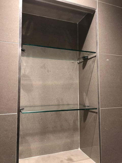 Glass shelving in a bathroom wall niche