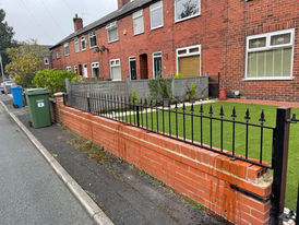 Wrought iron fence detail above a low brick wall surrounding the front of a local property