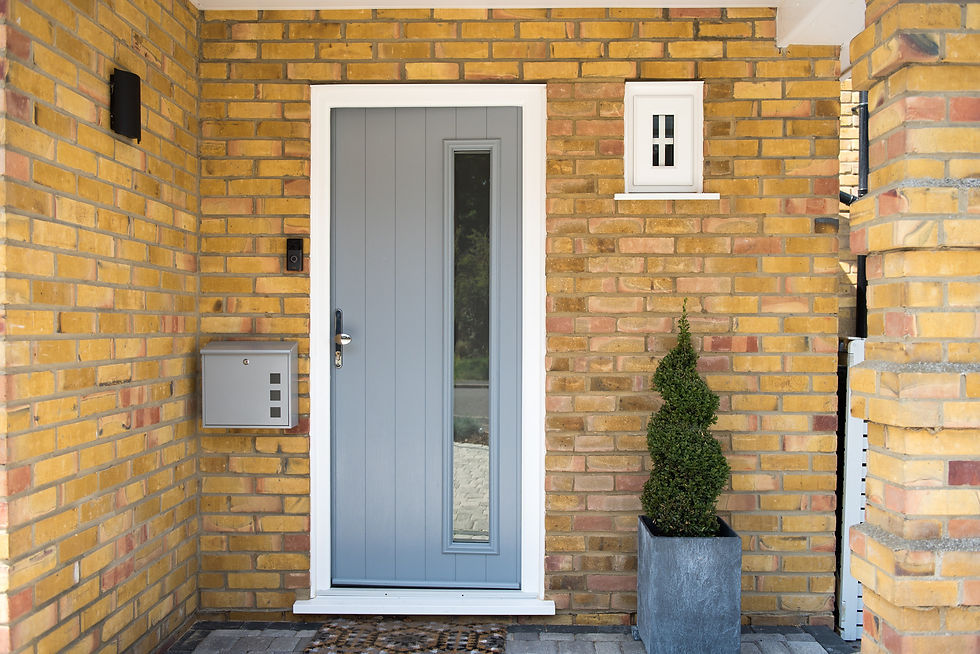 A general view of an entrance with a grey composite front door, mail box and topiary spira