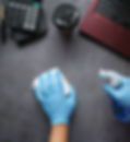 Gloved hands spraying desk surface with cleaning solution
