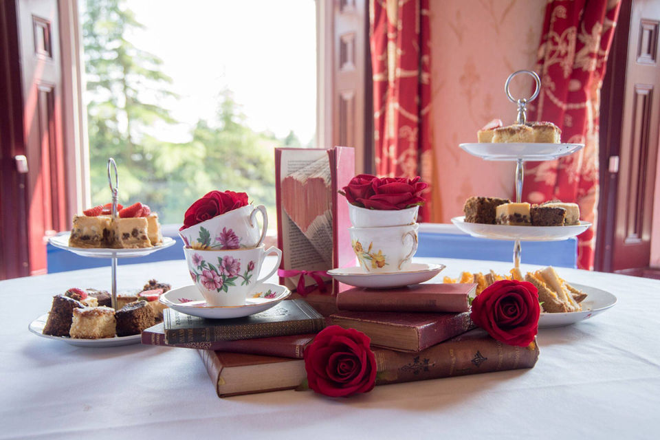 Whimsical wedding table set-up - with desserts on two-tier stands, books stacks, and roses