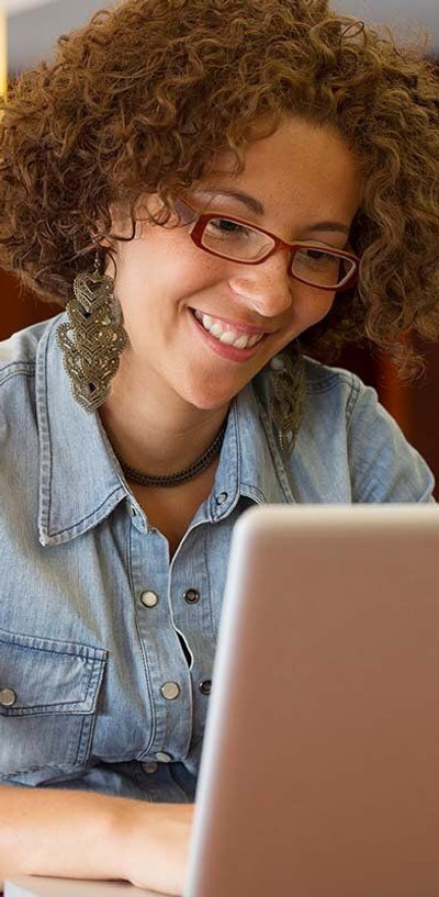 A curly-haired female counselling student hard at work on her laptop